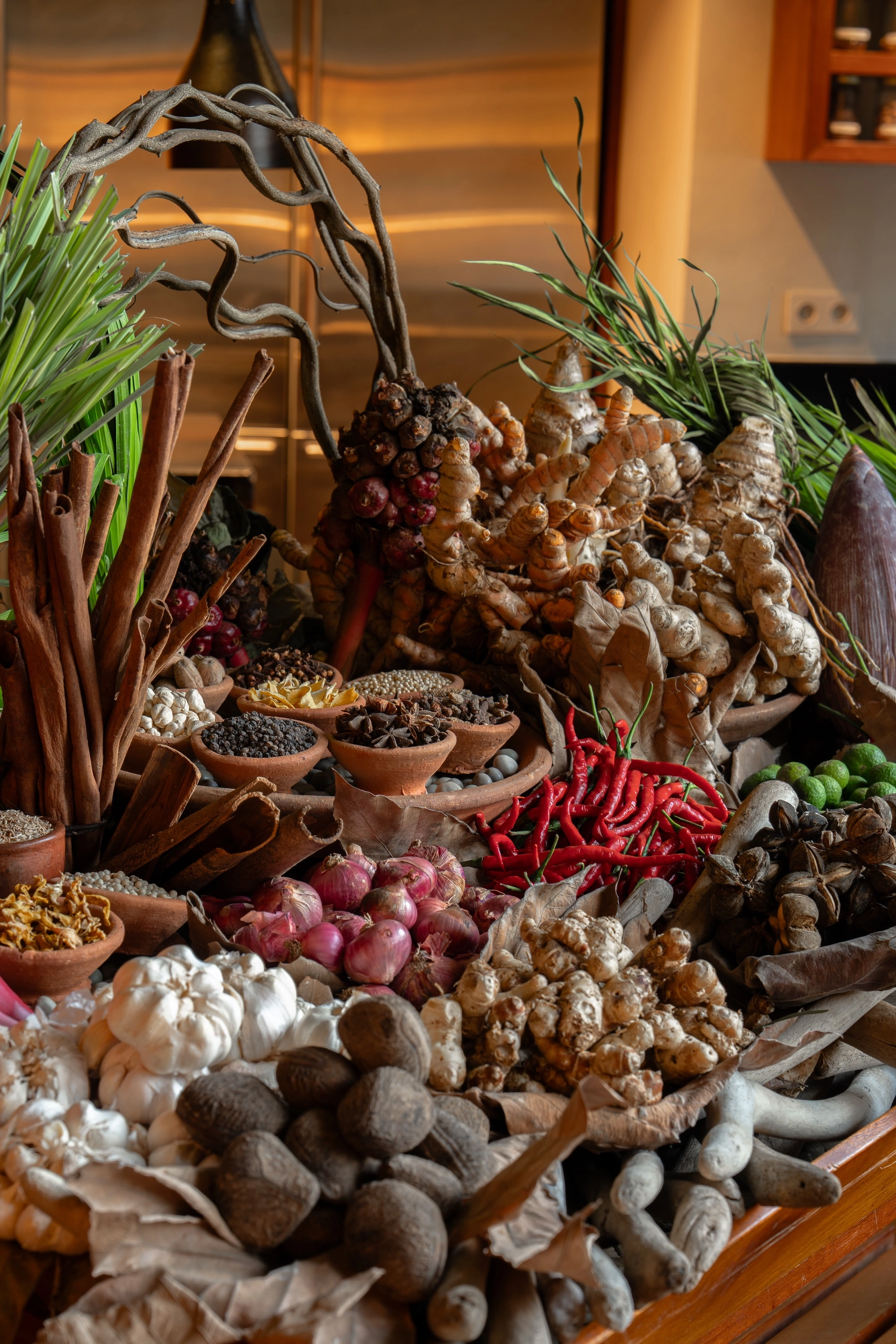 The class's ingredients heaped on the table — ginger, turmeric, cinnamon bark, shallots, garlic, red chillies and bowls of whole spices