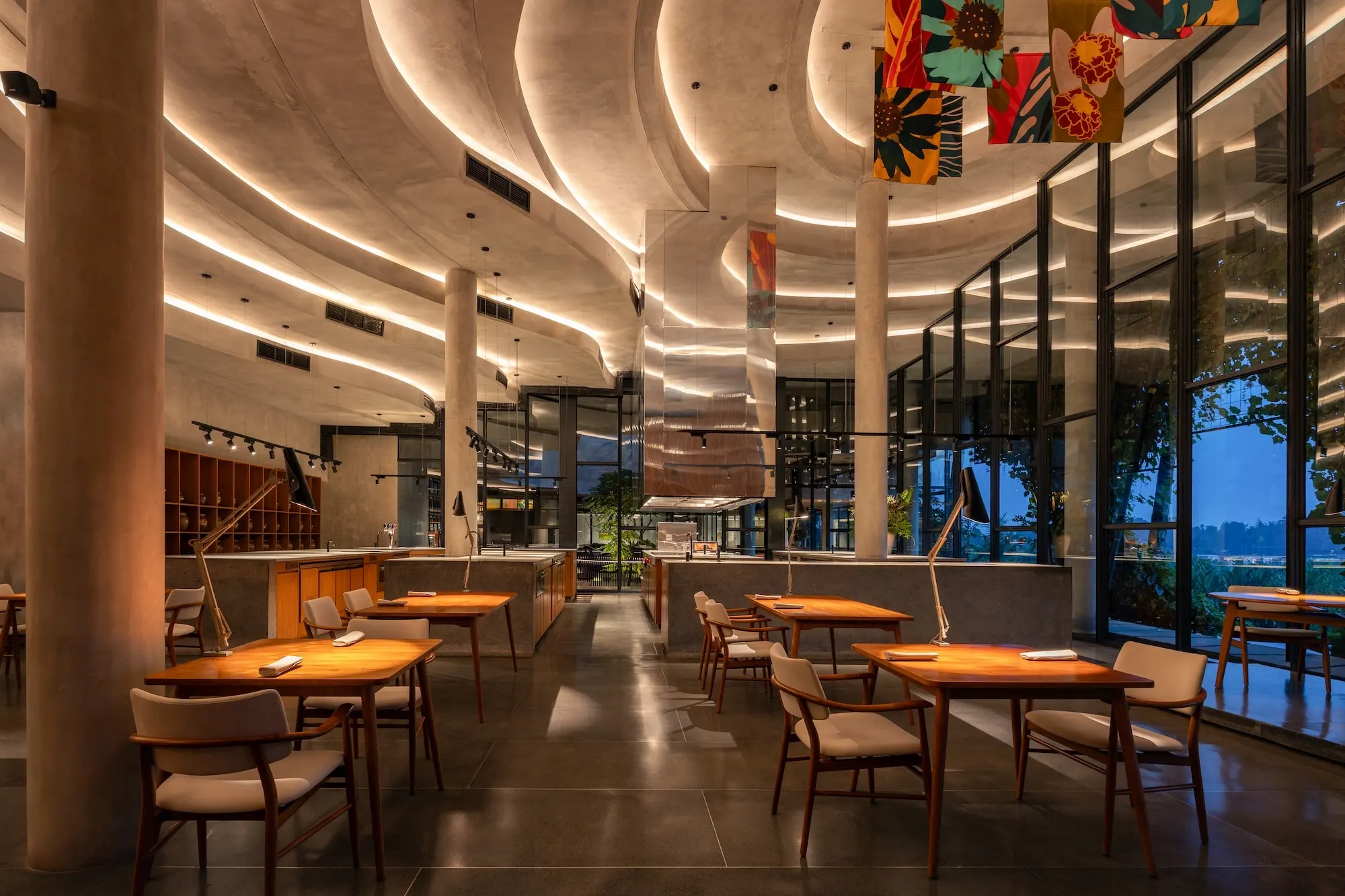 Locavore NXT's dining room — layered sculptural ceilings over timber tables, glass walls to the valley